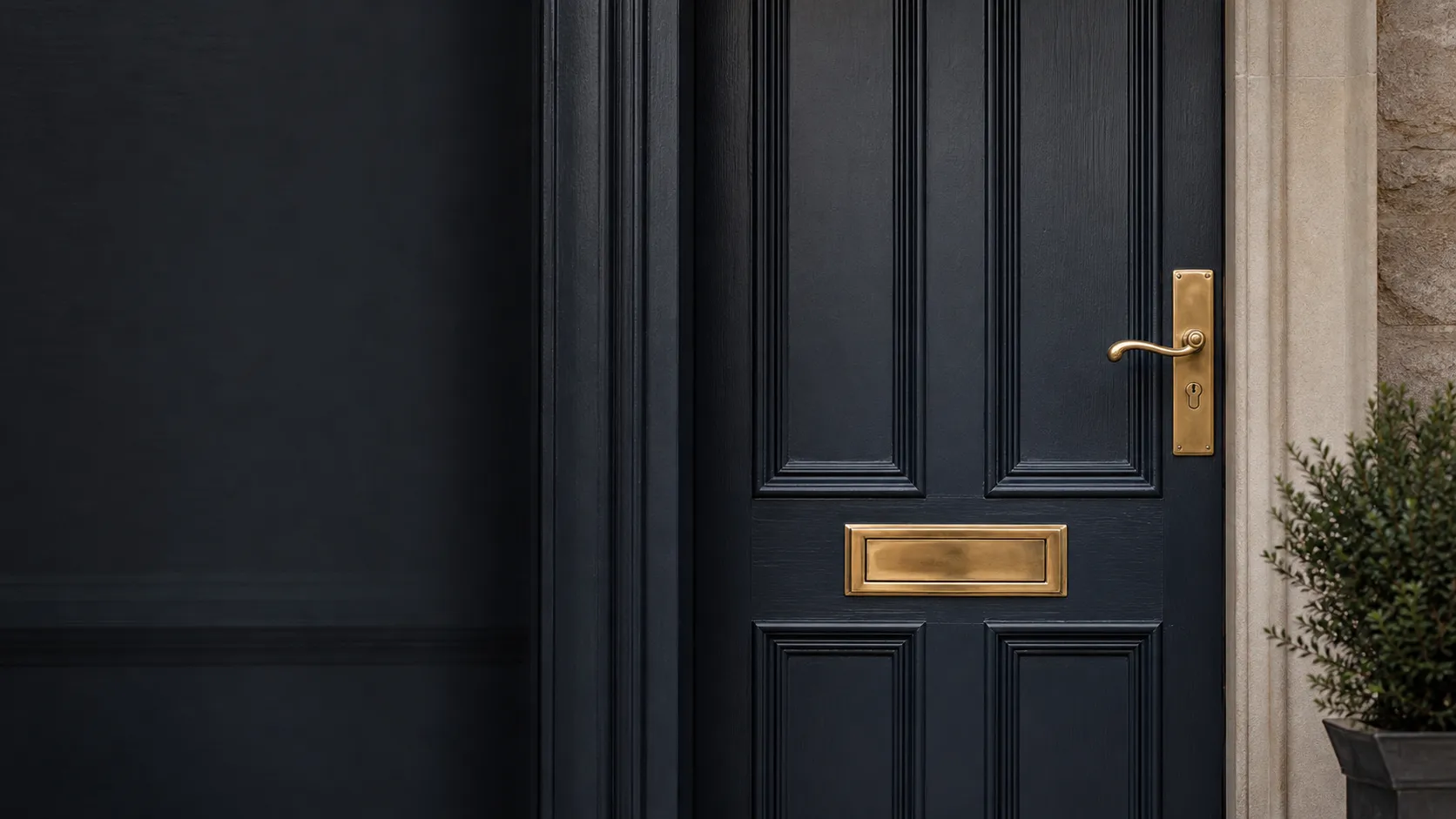 A finished dark timber front door with polished brass hardware